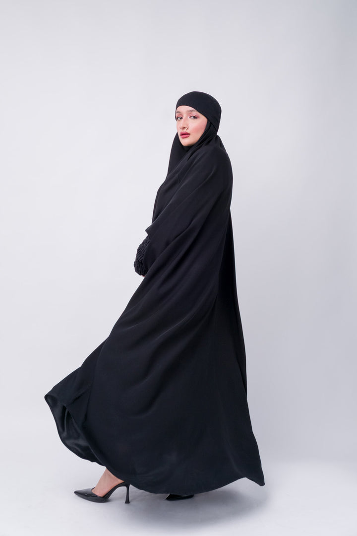 Islamic black khimar abaya with long loose-fit cut and textured sleeves, ideal for hijab and jilbab style lovers.