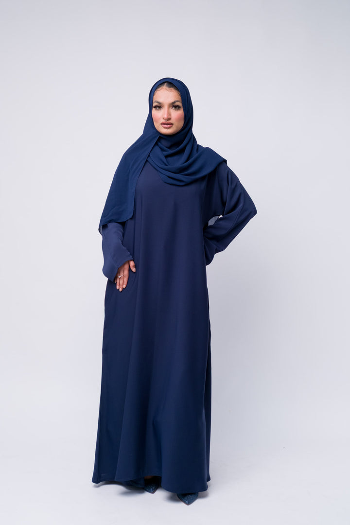 Flowy navy blue abaya with scarf, classic Islamic dress for women, ideal for prayer or events.