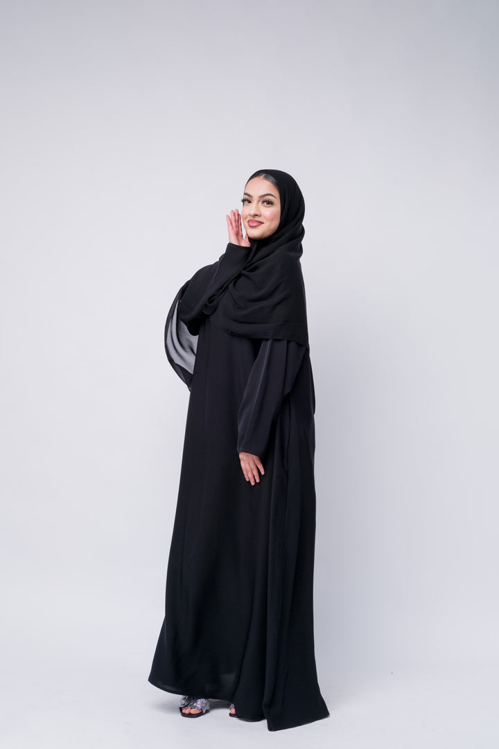 Classic black abaya with sleek silhouette and hijab, great for modest fashion and Muslim women's wear.