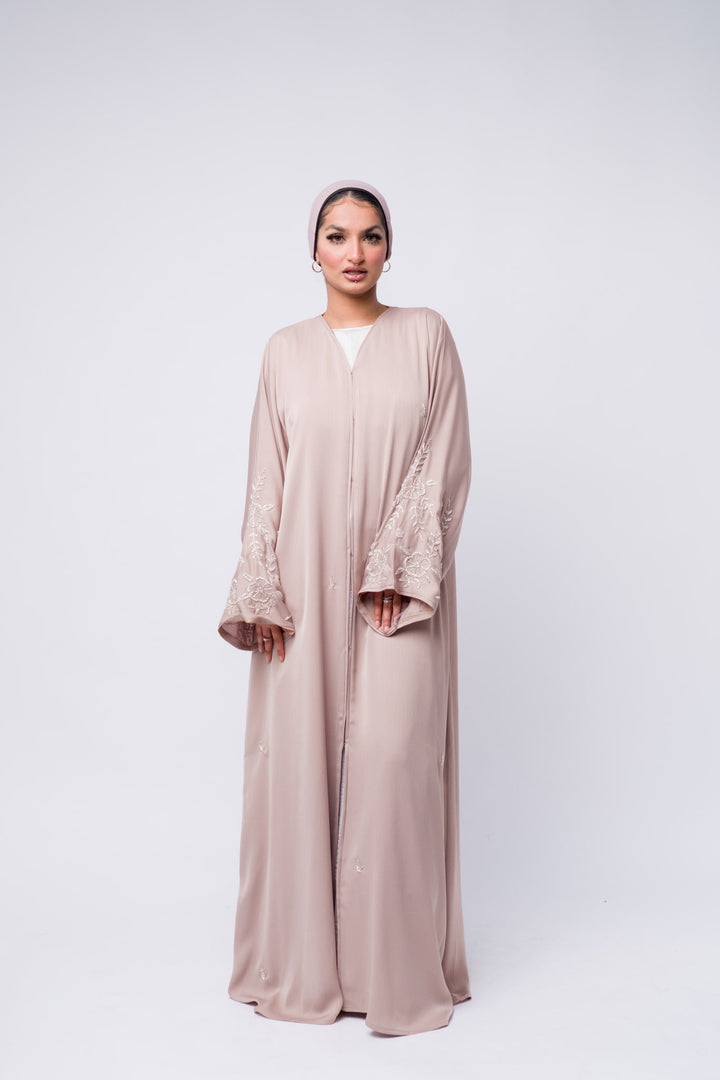 Stylish nude abaya with detailed floral sleeve embroidery, perfect for modest fashion lovers.