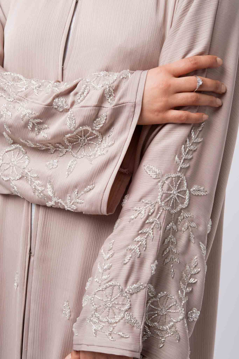 Modest nude pink open abaya with intricate white embroidery, ideal for weddings and evening wear.
