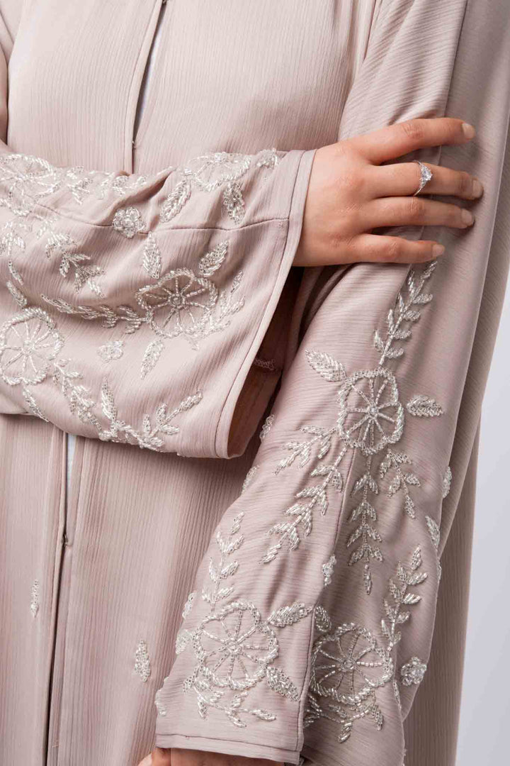 Modest nude pink open abaya with intricate white embroidery, ideal for weddings and evening wear.