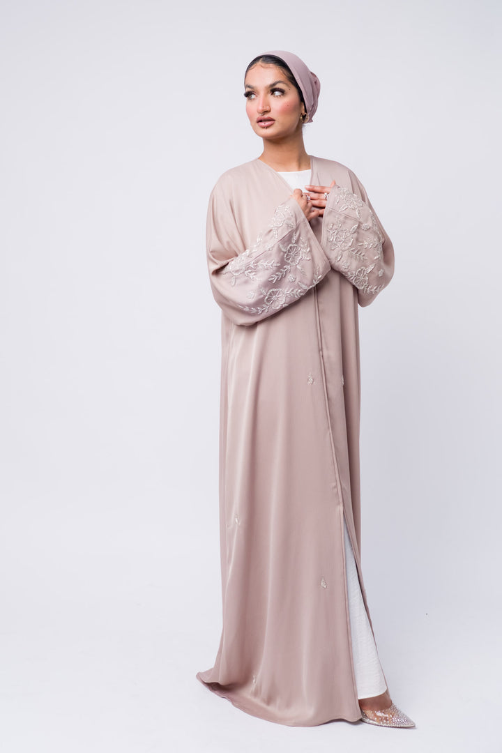 Modest fashion nude abaya with delicate floral embellishments on sleeves, lightweight and stylish. 