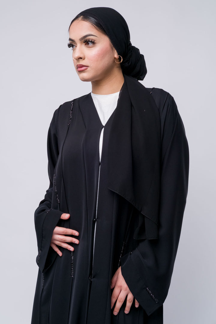 Elegant black abaya with subtle embellishments, ideal for modest wear and formal occasions.