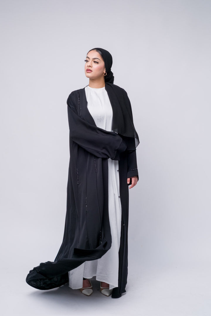 Black modest abaya with front button closure and shimmer accents, ideal for everyday elegance.