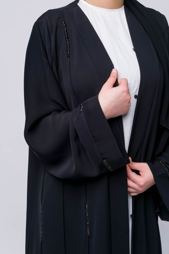 Flowing black abaya with modest design and sparkle trims, perfect for formal or casual wear.