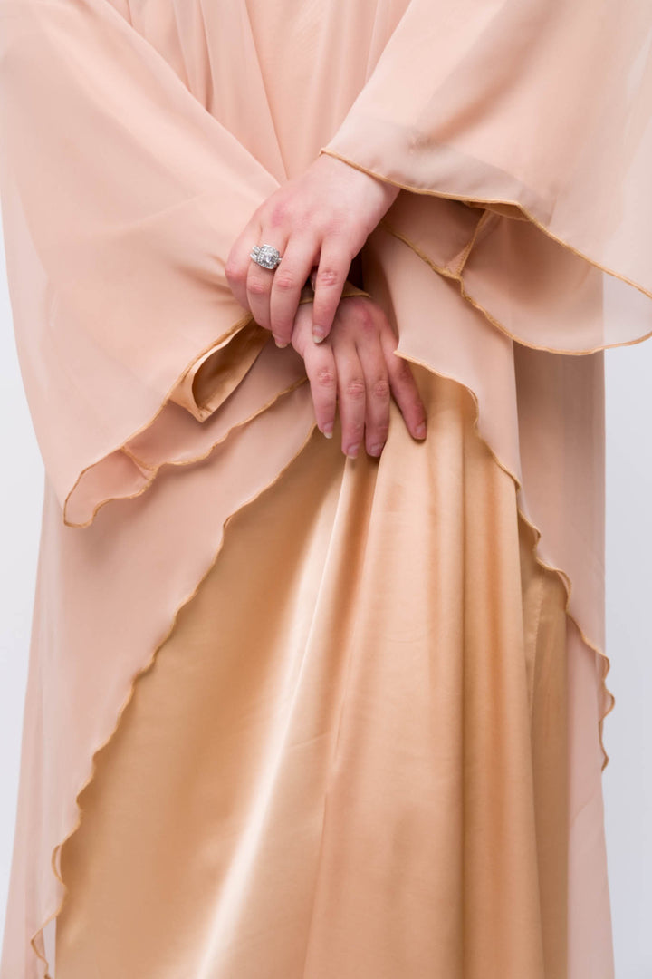 Lightweight peach abaya dress with high-low hem and layered design, hijabi outfit idea. 