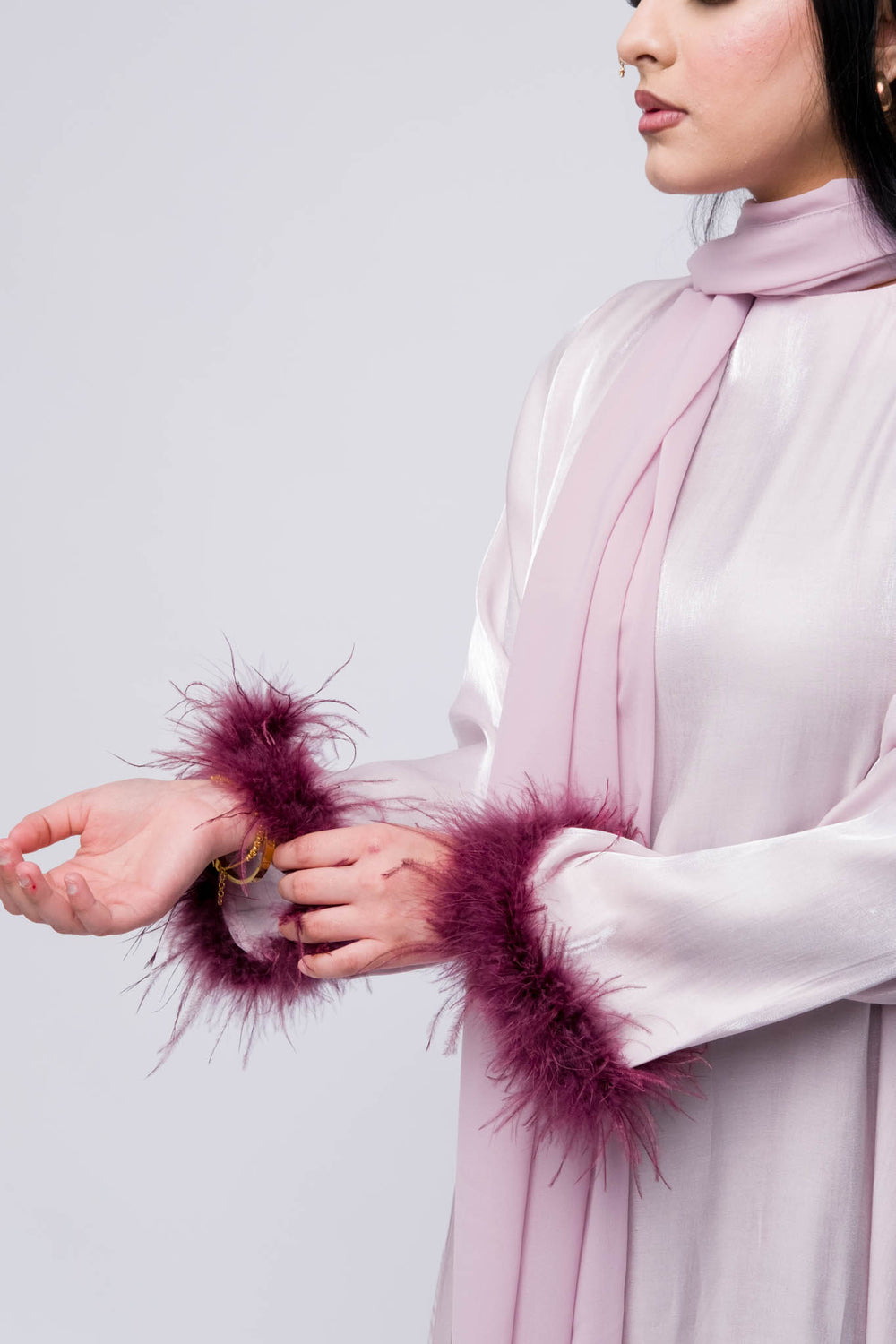 Luxury abaya in glossy lilac fabric with fluffy feather cuffs, modest wear, Eid outfit for women.