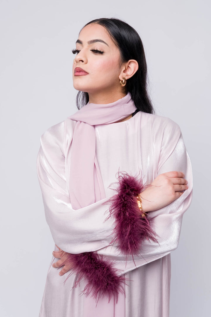 Flowing abaya in pastel lilac with bold feather cuffs, modern Muslim women’s fashion.